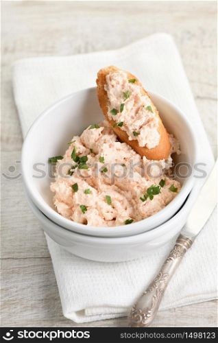 Salmon paste bowl with soft cheese and herb, toasted sliced ??bread, vintage knife with a textile napkin on a wooden table
