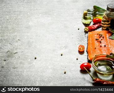Salmon raw fillet with tomatoes, olive oil and spices. On a stone background.. Salmon fillet with tomatoes, olive oil and spices.