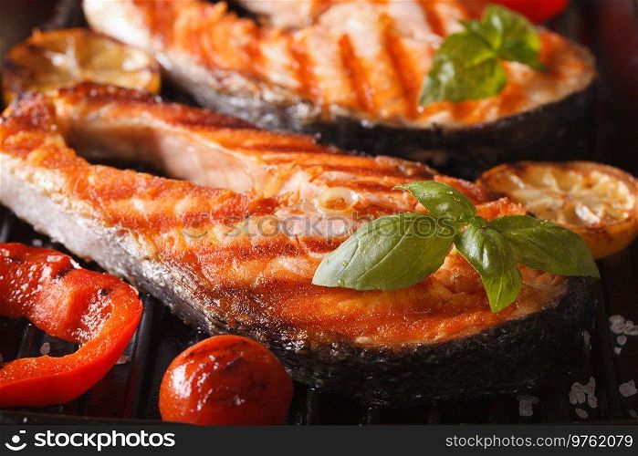 Salmon roasted in an oven with a butter, parsley and garlic. Portion of cooked fish and fresh lemon on a white plate