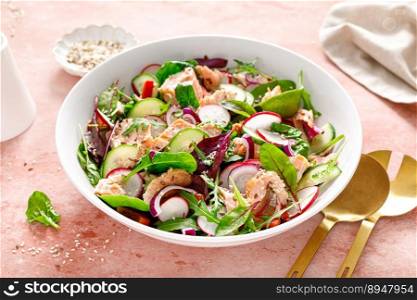 Salmon salad bowl with fresh radish, cucumber, red onion and green mixed leafy vegetables. Healthy diet food, lunch menu