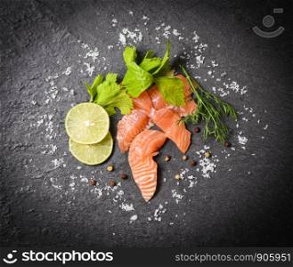Salmon Salad / Fish salmon fillet on black plate background - top view of raw salmon sashimi seafood with lemon herbs and spices