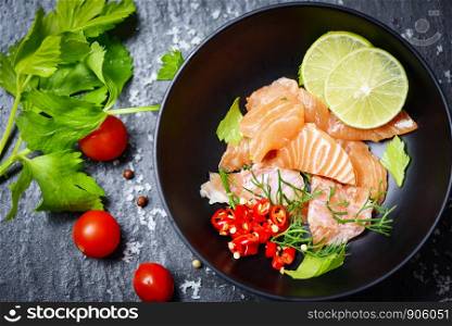 Salmon Salad / Fish salmon fillet on bolw and dark background / Close up of raw salmon sashimi seafood with lemon herbs and spices