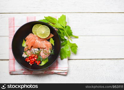 Salmon Salad / Fish salmon fillet on bolw wooden background / Close up of raw salmon sashimi seafood with lemon herbs and spices