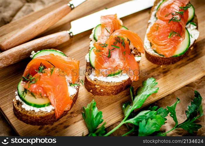 Salmon sandwich on a wooden cutting board. Macro background. High quality photo. Salmon sandwich on a wooden cutting board.