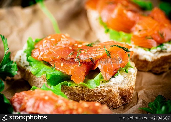 Salmon sandwich on paper. Macro background. High quality photo. Salmon sandwich on paper. Macro background.