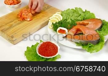 Salmon steak and red caviar, In the background female cutting fish steak