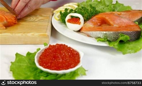 Salmon steak and red caviar, In the background female cutting fish steak, Dolly shot