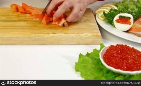 Salmon steak and red caviar, In the background female cutting fish steak, Dolly shot