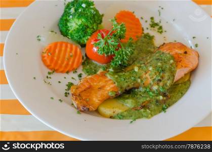 salmon steak. steak of salmon served with green sauce and vegetable on plate
