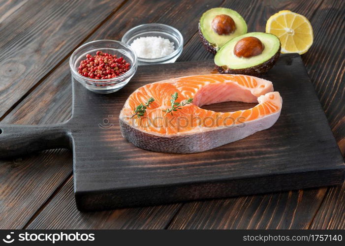 Salmon steak with avocado and seasonings on the wooden board