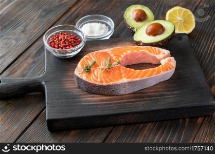 Salmon steak with avocado and seasonings on the wooden board