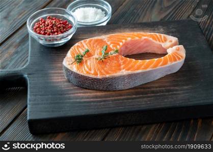 Salmon steak with fresh thyme and seasonings on the wooden board
