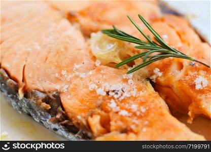 Salmon steak with herbs and spices rosemary on plate background / Close up cooked salmon fish fillet steak seafood