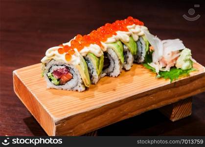 Salmon Tuna salmon roe and avocado maki roll sushi on wooden plate