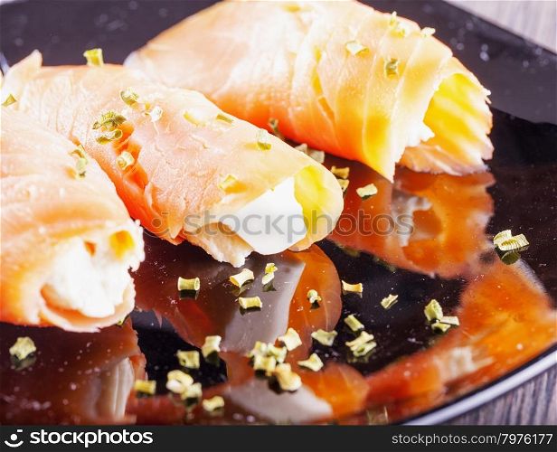 Salmon with cheese, over black reflecting plate, horizontal image