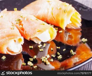 Salmon with cheese, over black reflecting plate, horizontal image