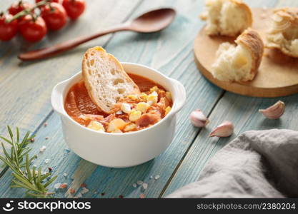 Salmorejo, spanish cold tomato soup, served in bowl with ham and bread