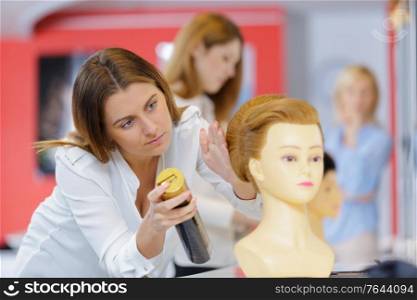 salon apprentice spraying chemical on mannequins wig