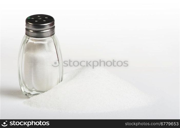 Salt and saltshaker on white background .