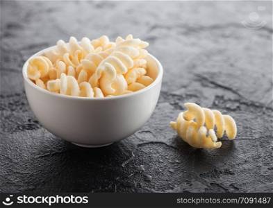 Salt and vinegar potato twirls in white bowl, classic snack on black kitchen table.
