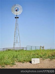 salt block for cattle and windmill pumping water in green prairie in Colorado - Pawnee National Grassland in early summer