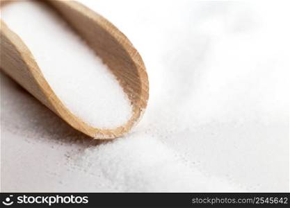 Salt grain in wooden spoon top view on white background , flat lay.. Salt grain in wooden spoon top view on a white background , flat lay.