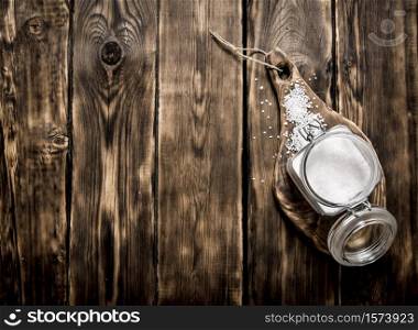 Salt in a glass jar on a wooden Board. On a wooden background.. Salt in a glass jar on wooden Board