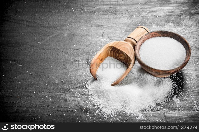 Salt in a wooden bowl. On the black chalkboard.. Salt in a wooden bowl.