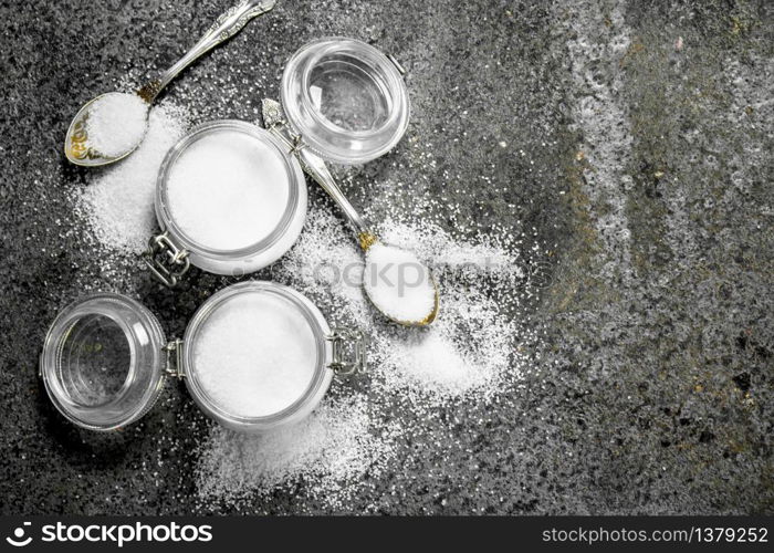 Salt in jars and spoons. On rustic background.. Salt in jars and spoons.