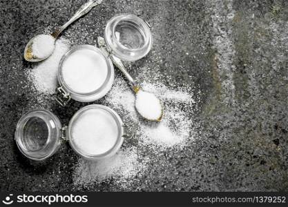 Salt in jars and spoons. On rustic background.. Salt in jars and spoons.