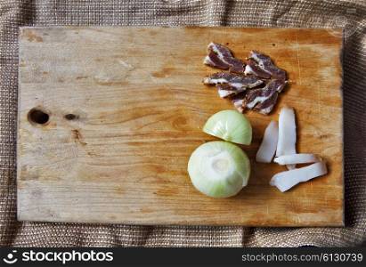 Salt meat and ingredients for cooking around cutting board on rustic background, top view, place for text