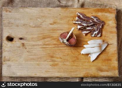 Salt meat and ingredients for cooking around cutting board on rustic background, top view, place for text