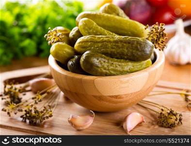Salted cucumbers in a bowl on wooden table