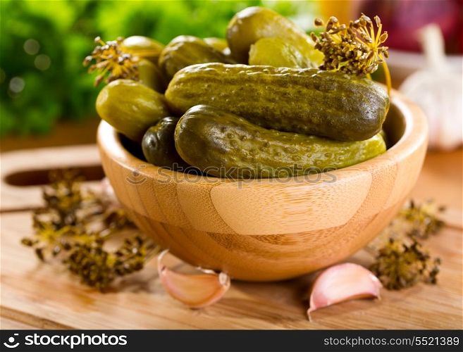 Salted cucumbers in a bowl on wooden table
