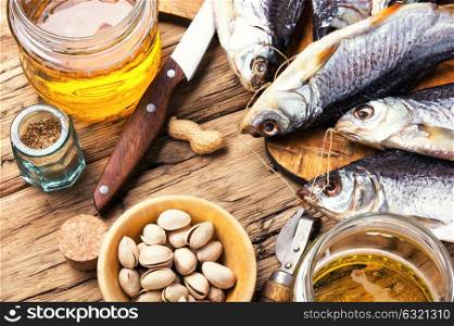 salted fish and beer. glass of beer, salted fish and nuts on wooden table