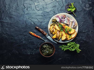 Salted herring fish with roasted potatoes on the plate.Copy space. Salted herring with baked potatoes