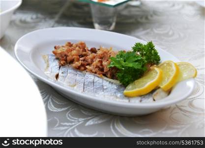 salted herring with fried onions and lemon on plate