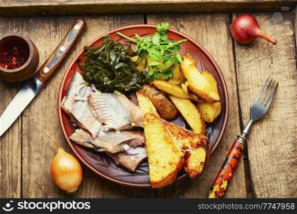 Salted herring with garnish, seafood. Marinated herring fish with roasted potatoes. Salted herring with baked potatoes