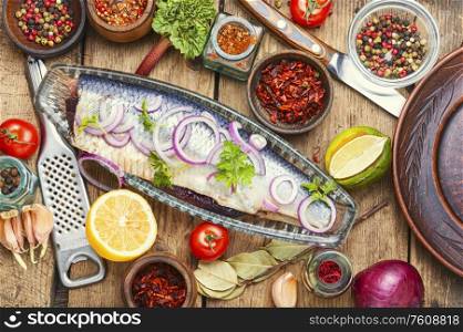 Salted herring with red onion on old wooden background.Rustic food. Salted herring on a wooden table