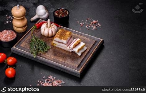 Salted Lard, Raw Pork with Spices on Wooden Cutting Board Studio Photo. Smoked lard, bacon, half a piece, on a wooden dark cutting board