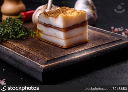 Salted Lard, Raw Pork with Spices on Wooden Cutting Board Studio Photo. Smoked lard, bacon, half a piece, on a wooden dark cutting board