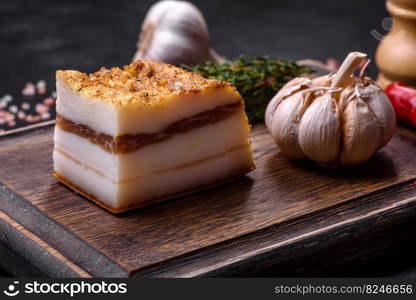 Salted Lard, Raw Pork with Spices on Wooden Cutting Board Studio Photo. Smoked lard, bacon, half a piece, on a wooden dark cutting board