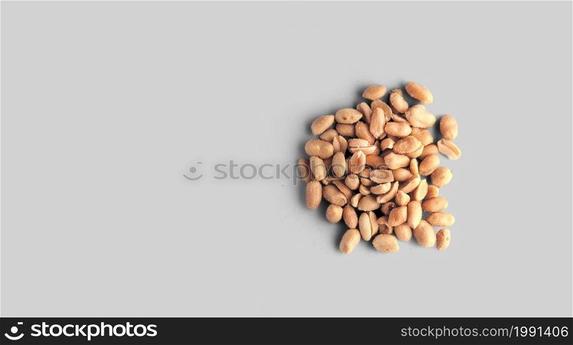 Salted pile of Peanuts in isolated over white textured background, top view, close-up.
