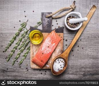 salted salmon  fillet on a cutting board with delicious ingredients for cooking on wooden rustic background top view