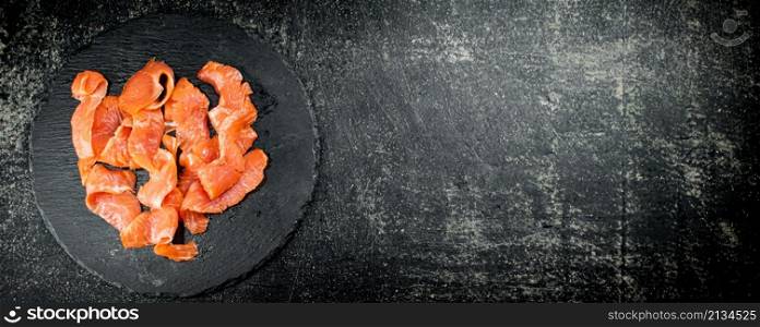 Salted salmon on a stone board. On a black background. High quality photo. Salted salmon on a stone board.