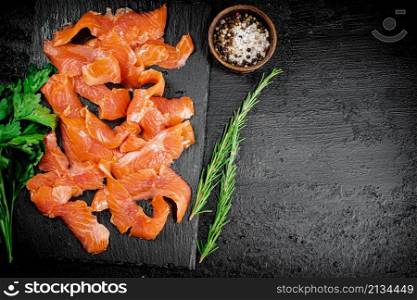Salted salmon on a stone board with spices. On a black background. High quality photo. Salted salmon on a stone board with spices.