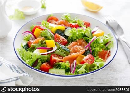Salted salmon salad with fresh green lettuce, cucumbers, tomato, bell pepper and red onion. Ketogenic, keto or paleo diet lunch bowl