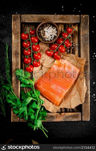 Salted salmon with parsley and tomatoes on a wooden tray. On a black background. High quality photo. Salted salmon with parsley and tomatoes on a wooden tray.