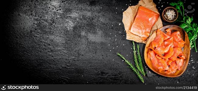 Salted salmon with rosemary, parsley and spices. On a black background. High quality photo. Salted salmon with rosemary, parsley and spices.