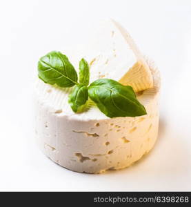 Salted soft cheese with basil leaf on the white. Salted soft cheese